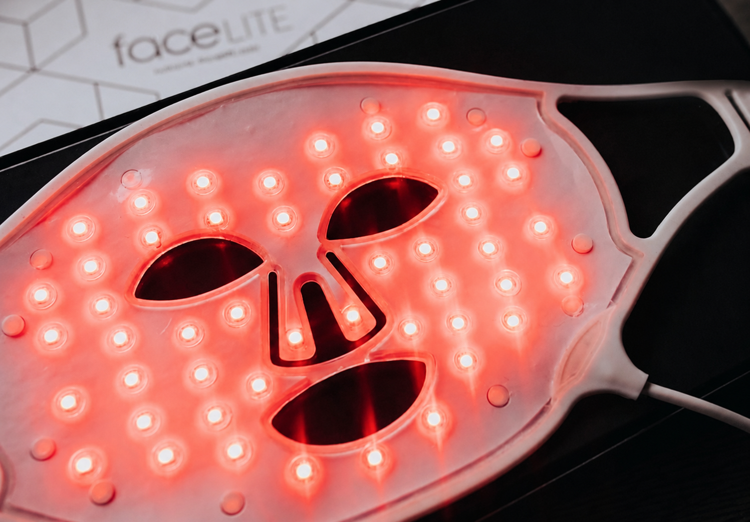Het FaceLITE LED-masker met brandende rode leds naast de bediening